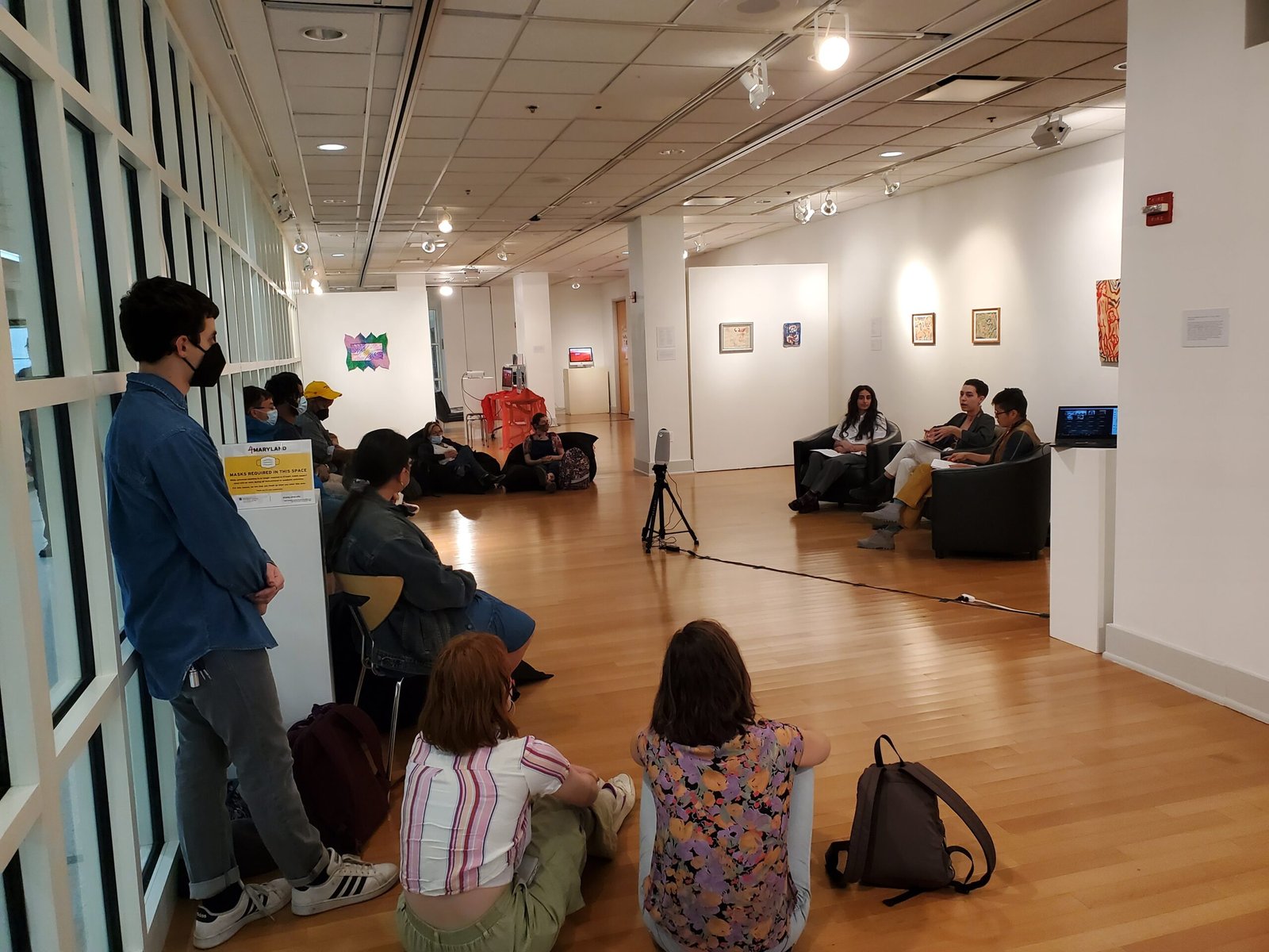 Transverse Co-op co-founders speak in front of an audience in a gallery.