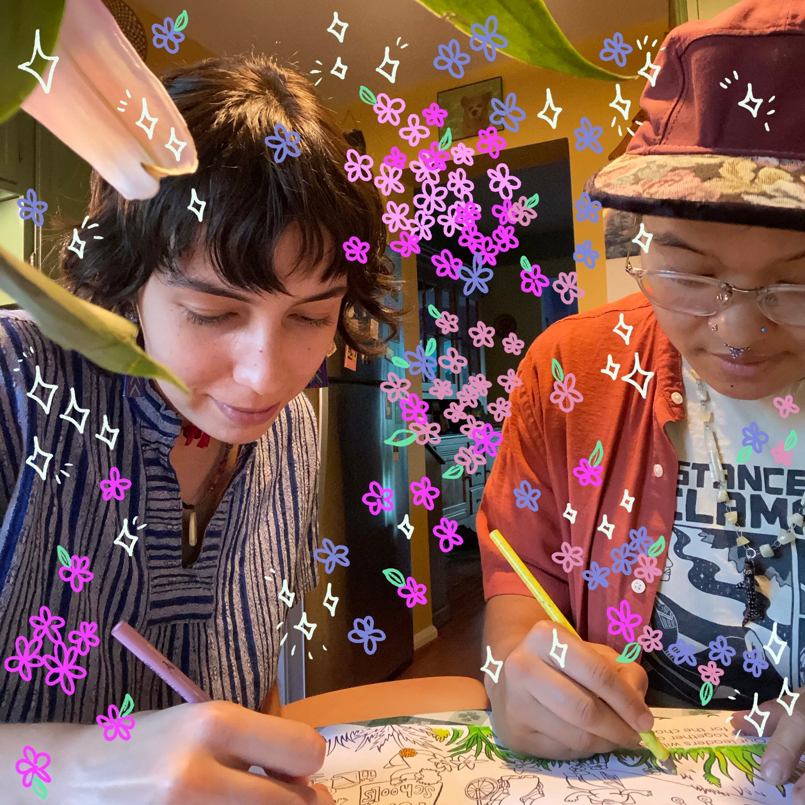 Co-founders and worker-owners Ellie and Camila color their commissioned coloring book. Drawings of flowers and sparkles are transposed on top of the image.